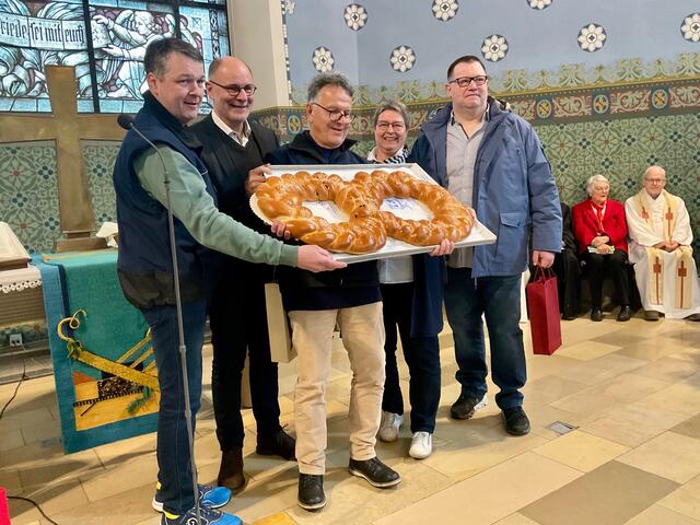 Beifall gab es in der Vesperkirche für das bewährte Backstuben-Team mit Vulkanbäcker und Brotsommelier Eric Stadelhofer, Singens Oberbürgermeister Bernd Häusler, Vesperkirchen-Urgestein Ulrich Kaiser, Claudia Graf von den Katholischen Frauengemeinschaft Deutschland und Andreas Auer (von links), legendärer Innenstadt-Bäcker, dem aktuell die besten Genesungswünsche im Kirchenrund galten - hier mit ihrem beeindruckenden Zopf in Form einer Acht, welche die achte Vesperkirche symbolisch bezeugt. | Foto: Bernhard Grunewald