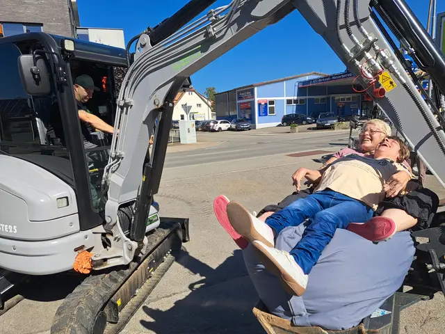 Stefanie Bach ist überglücklich, als ihr Traum in Erfüllung geht. Zusammen mit ihrer Betreuerin Claudia Wils-Keiling darf sie in der Baggerschaufel von Lukas und Alexander Lohr mitfahren. | Foto:  Sebastian Ridder