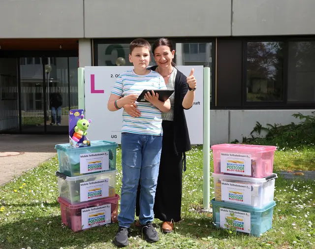 UK-Fachkraft und junger Patient freut sich über gefüllte Teilhabeboxen Deutsche Postcode Lotterie. | Foto: Andrea Jagode
