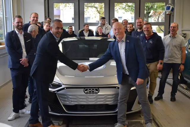 Obermeister Paulo Rodrigues von der Kfz-Innung Bodensee Hochrhein Schwarzwald (links) und Schulleiter Stefan Fehrenbach von der Hohentwiel-Gewerbeschule Singen schütteln die Hände über dem neuen E-Auto, das die Innung der Schule gespendet hat. | Foto: Tobias Lange