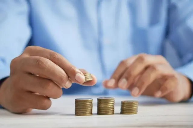 Foto: Quelle: Foto von Towfiqu barbhuiya auf Unsplash https://unsplash.com/de/fotos/eine-person-die-munzen-auf-einem-tisch-stapelt-jpqyfK7GB4w