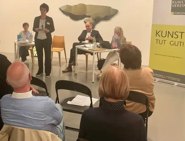 Einen umfassenden Jahresbericht 2025 erstattete Vorsitzende Ulrike Veser (stehend) der Mitgliederversammlung des Kunstvereins Singen e.v. im Kunstmuseum, begleitet und unterstützt von ihren Vorstandsmitgliedern Martina Fahr- Rackow als Schatzmeisterin (li), Oberbürgermeister Bernd Häusler und Schriftführerin Catharina Scheufele. | Foto: Bernhard Grunewald