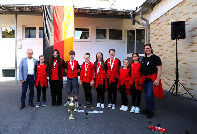 Bürgermeister Manfred Ossola, Helena Schroth, Basandra Mirzai, Lennon Keller, Landelin Lürig, Mara Moll, Haylie Rietschle, Amelie Biedermann, Lucina Quini und Cheftrainerin Katja Gaißer (es fehlt Lotta Leitz) – in Front: Der Gold-Pokal 2025 von German Cycling (BDR) | Foto: Wilfried Schwarz