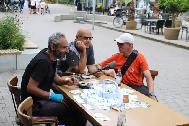 Shooresh Fezoni und Ralf Wendt unterhalten sich am "parasitären Stammtisch" mit Passantinnen und Passanten in der Radolfzeller Fußgängerzone über Heimat, Leerstand und Gestaltungsräume. | Foto: Eron Metolli