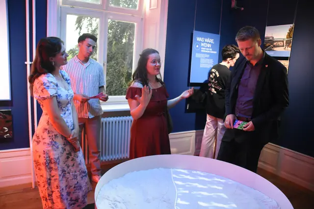 Oberbürgermeister Simon Gröger (rechts) blickt gemeinsam mit den beiden Studierenden Anna Sophie Graßmann (links) und Anna-Lena Kraschina (Mitte) anhand eines 3D-Modells auf die Zukunft von Radolfzell und dem Bodensee in der Ausstellung "So! Oder Anders?" | Foto: Philipp Findling
