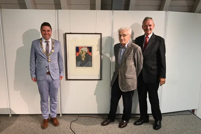 Bürgermeister Holger Mayer (links), Hans Geissler (Mitte) und Bernhard Hertrich (rechts) umrahmen eine der wenigen farbigen Druckgraphiken von Erich Heckel. | Foto: Philipp Findling